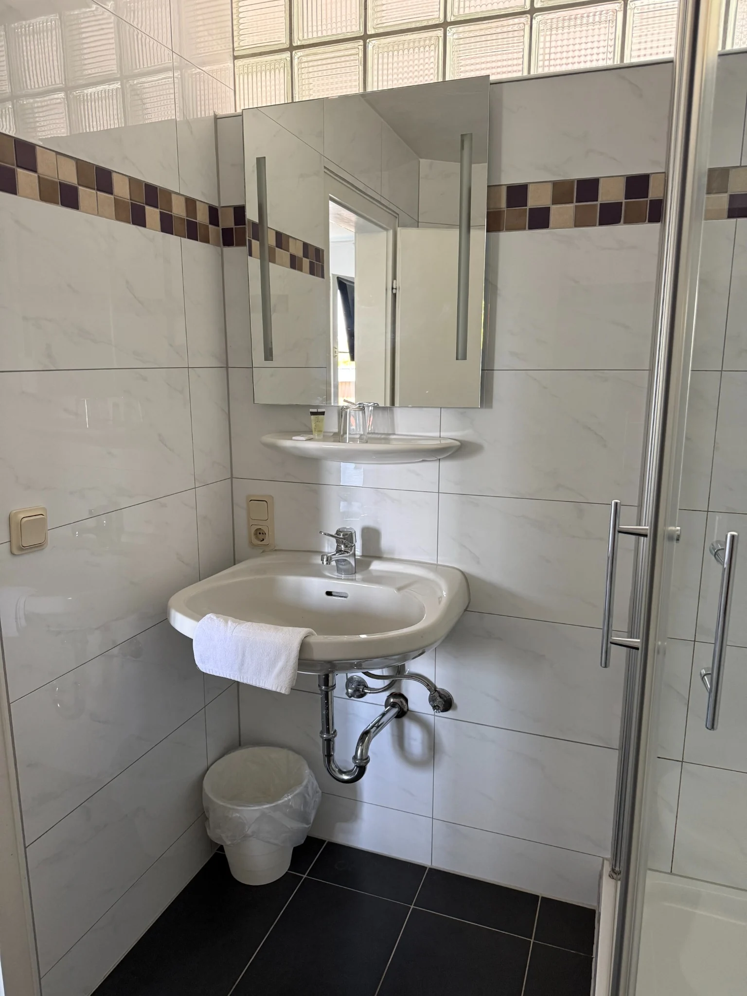 Waschbecken und Dusche im Badezimmer des Einzelzimmers
