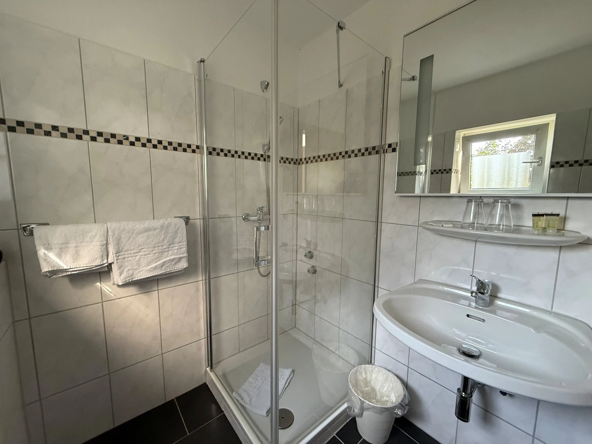 Dusche und Waschbecken im Badezimmer des Zweibettzimmers